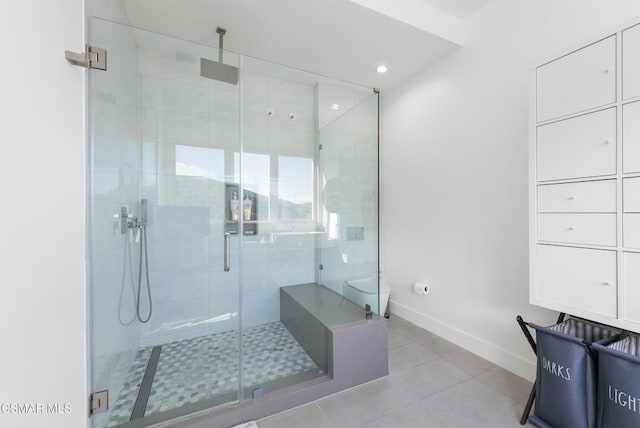 bathroom with toilet, tile patterned floors, and a shower with door