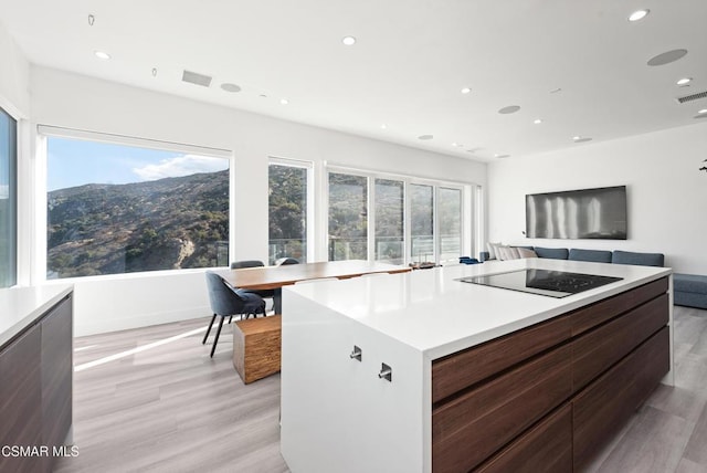 kitchen with black electric stovetop, plenty of natural light, a center island, and light wood-type flooring