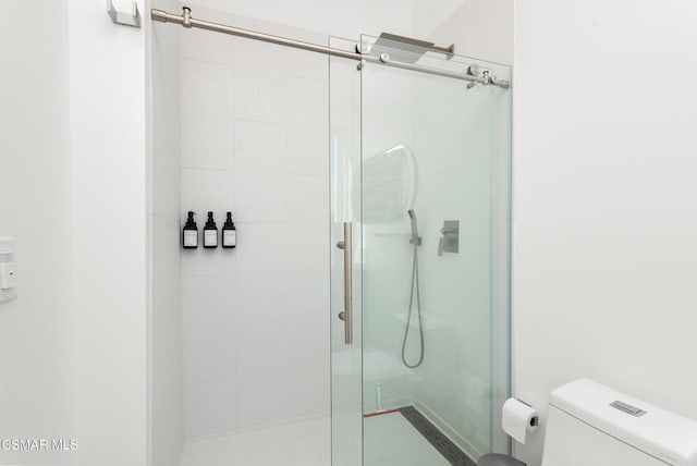 bathroom featuring toilet and a shower with door