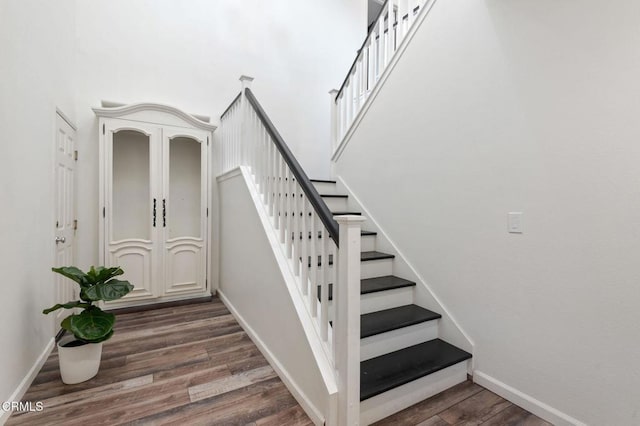 stairway featuring wood-type flooring and a high ceiling