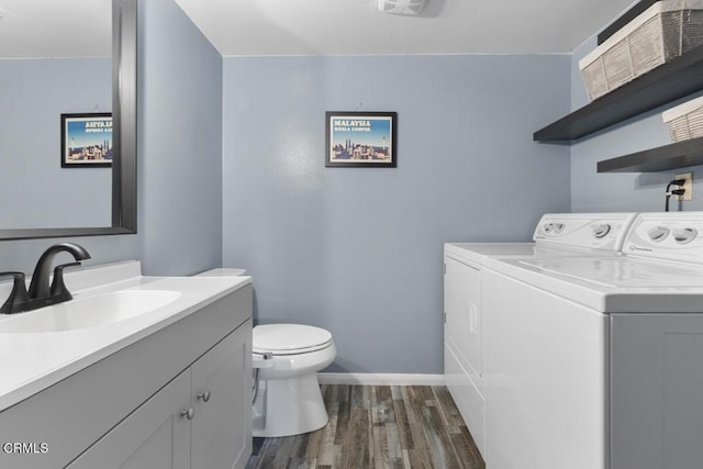 bathroom with baseboards, toilet, wood finished floors, vanity, and separate washer and dryer