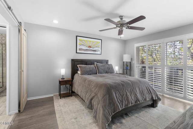 bedroom featuring a barn door, recessed lighting, wood finished floors, a ceiling fan, and baseboards