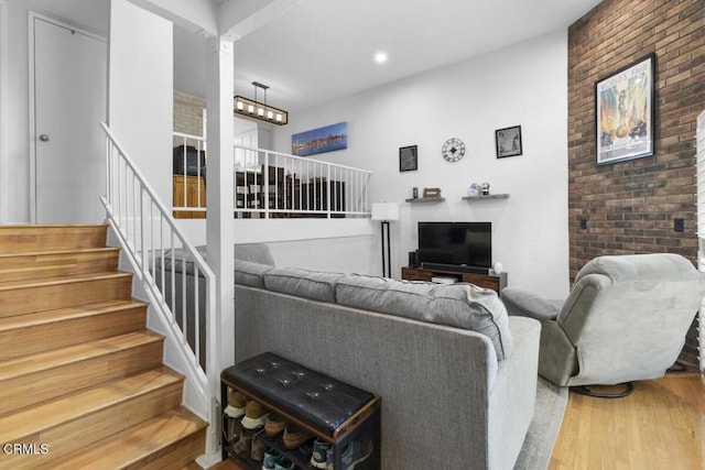 living room featuring stairs, recessed lighting, brick wall, and wood finished floors