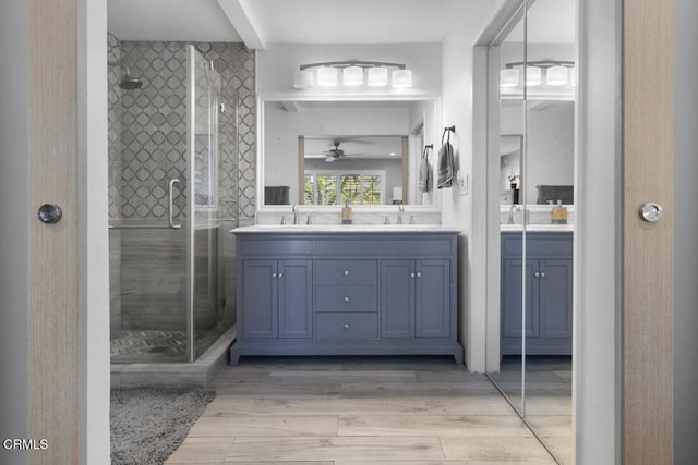 bathroom with double vanity, a shower stall, and a sink