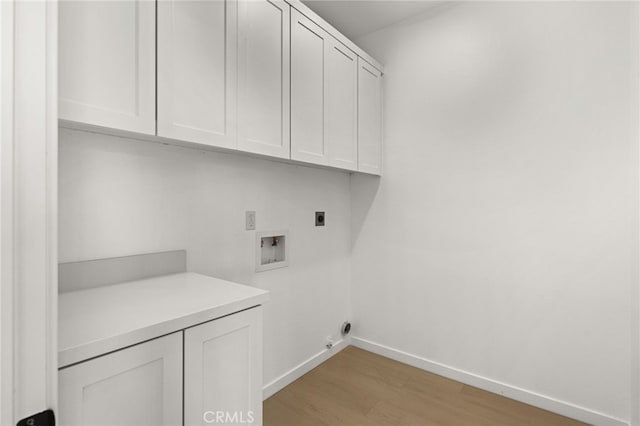 clothes washing area featuring electric dryer hookup, baseboards, cabinet space, and washer hookup