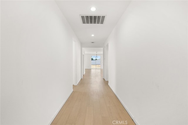 corridor with light wood-type flooring, visible vents, recessed lighting, baseboards, and a chandelier