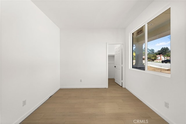 unfurnished room with light wood-type flooring and baseboards