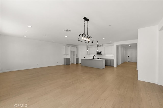 unfurnished living room with light wood-type flooring, visible vents, baseboards, and recessed lighting