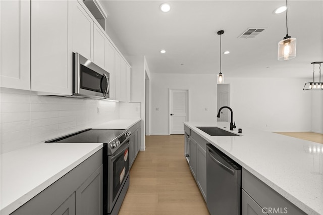 kitchen featuring visible vents, gray cabinets, a sink, appliances with stainless steel finishes, and light countertops