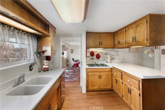 kitchen with backsplash, black gas cooktop, sink, and light wood-type flooring