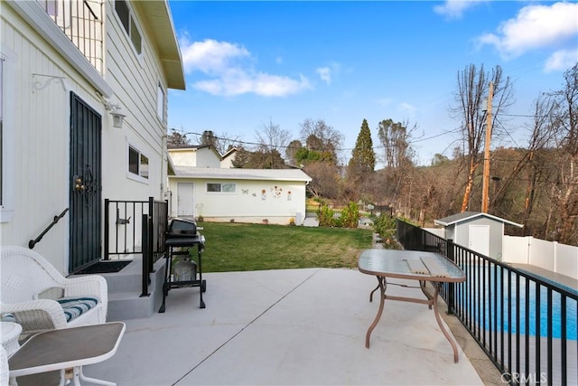 view of patio with area for grilling, a storage unit, and a fenced in pool