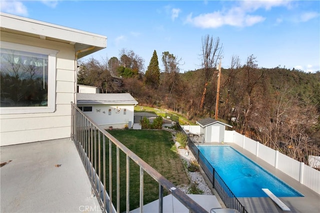 view of pool featuring a diving board, a yard, and a shed