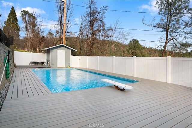 view of swimming pool with a shed, a diving board, and a deck