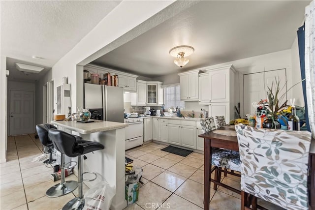 kitchen with white cabinetry, kitchen peninsula, white gas stove, and light tile patterned flooring