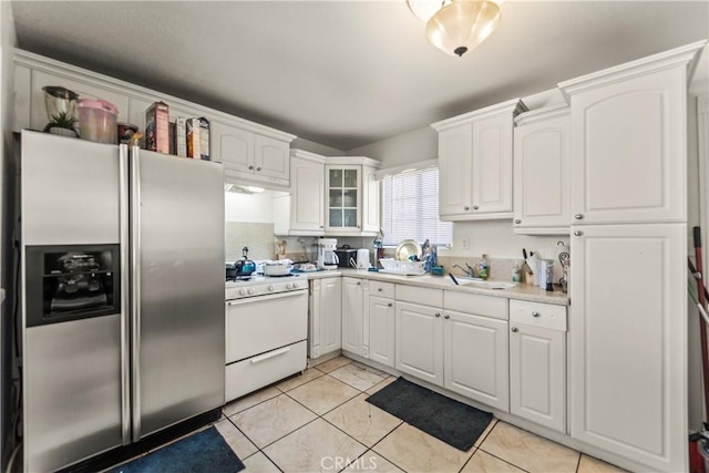 kitchen featuring white cabinetry, stainless steel fridge, white gas range, and light tile patterned floors