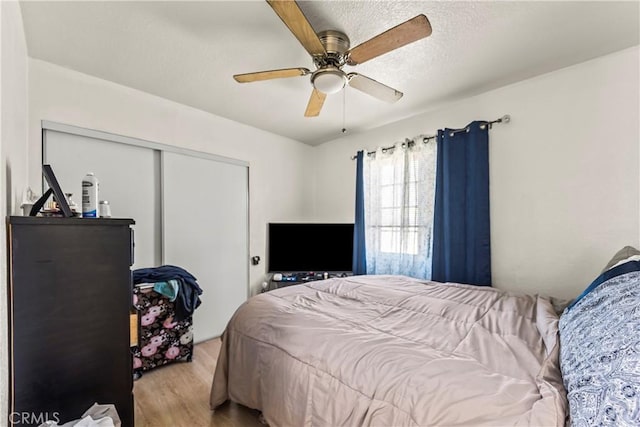 bedroom featuring a textured ceiling, light hardwood / wood-style floors, a closet, and ceiling fan