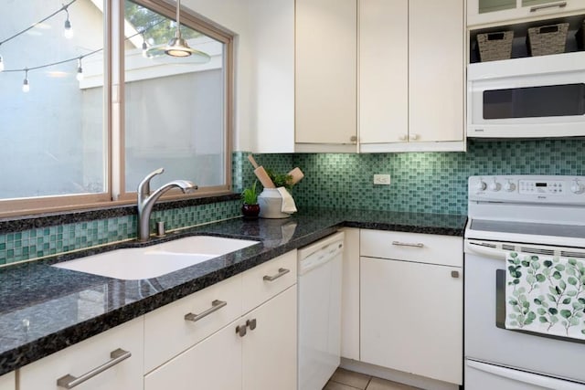 kitchen with white appliances, tasteful backsplash, white cabinetry, dark stone countertops, and sink