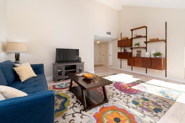 living room featuring high vaulted ceiling and light hardwood / wood-style floors