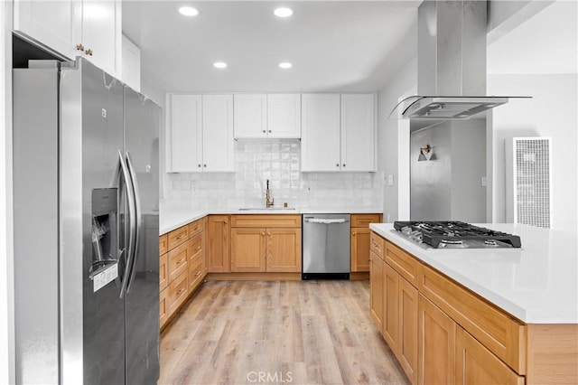 kitchen featuring stainless steel appliances, light countertops, a sink, and island range hood