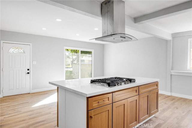 kitchen featuring stainless steel gas cooktop, light countertops, light wood finished floors, and island range hood