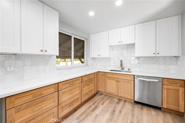 kitchen featuring light stone counters, a sink, stainless steel dishwasher, light wood-type flooring, and backsplash