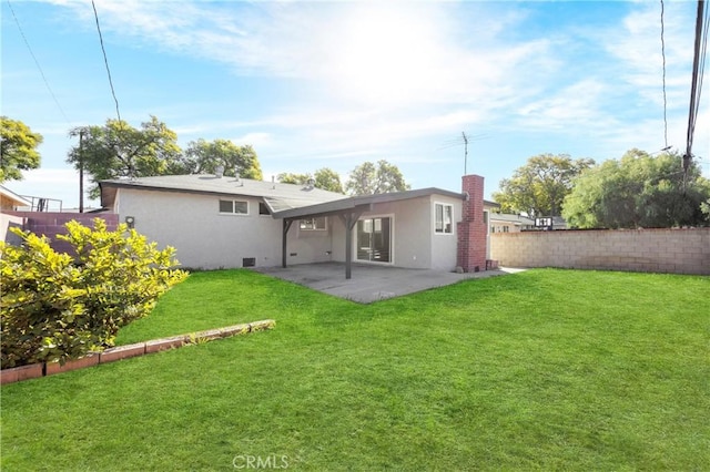 back of property with a lawn, a patio, a chimney, fence, and stucco siding