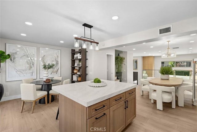 kitchen featuring a kitchen island, hanging light fixtures, and light hardwood / wood-style floors