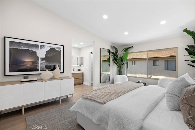 bedroom featuring connected bathroom, vaulted ceiling, and hardwood / wood-style flooring