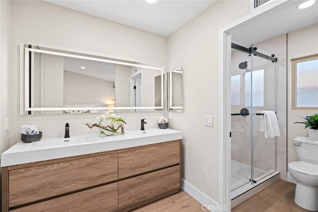 bathroom featuring hardwood / wood-style floors, vanity, toilet, and a shower with shower door