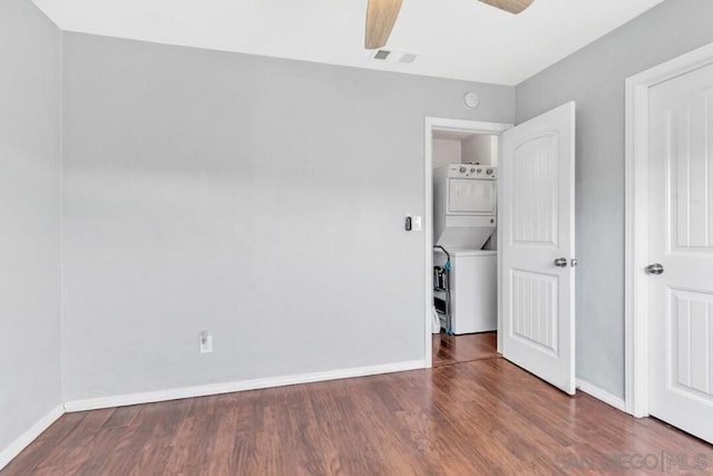 unfurnished bedroom featuring dark wood-type flooring, ceiling fan, and stacked washer / dryer