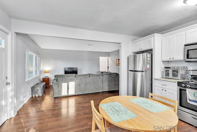 kitchen featuring light stone counters, a textured ceiling, dark hardwood / wood-style flooring, white cabinetry, and appliances with stainless steel finishes