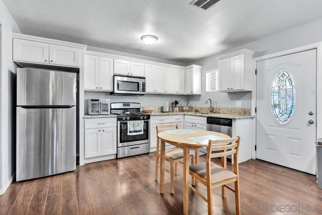 kitchen with stainless steel appliances, white cabinets, sink, and dark hardwood / wood-style floors