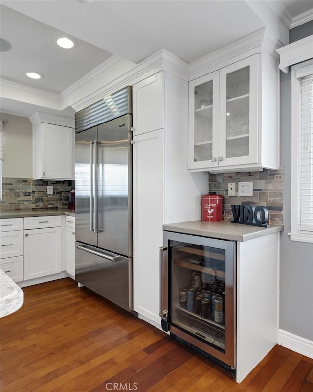 kitchen featuring backsplash, dark wood-type flooring, white cabinets, wine cooler, and built in refrigerator