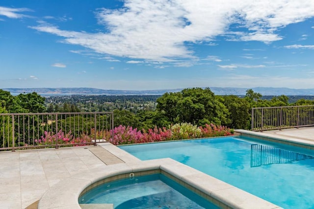 view of swimming pool featuring a mountain view and an in ground hot tub