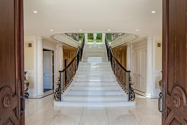 staircase featuring ornate columns and ornamental molding