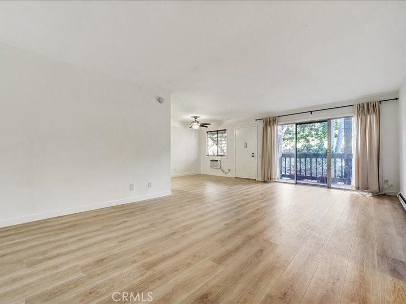 unfurnished living room with light wood-type flooring, baseboards, and a ceiling fan