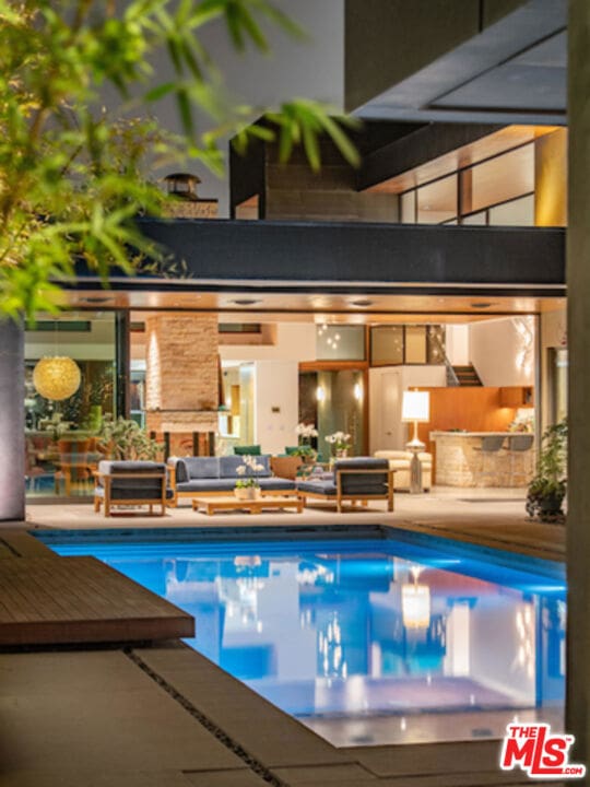 view of pool with an outdoor living space with a fireplace