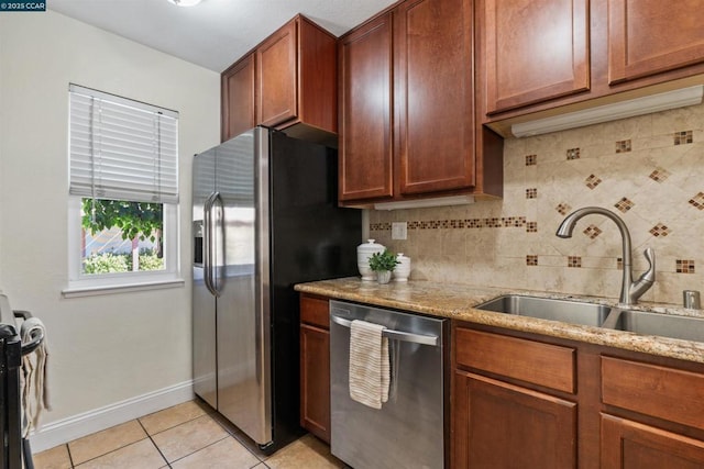 kitchen with decorative backsplash, appliances with stainless steel finishes, light stone counters, sink, and light tile patterned flooring