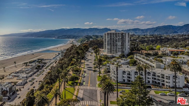 drone / aerial view with a water and mountain view and a view of the beach