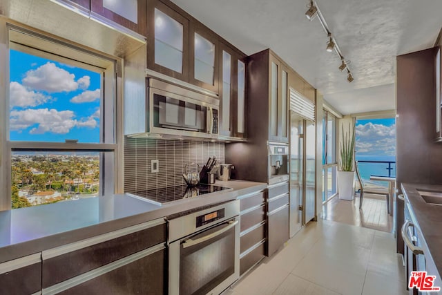 kitchen with backsplash, a healthy amount of sunlight, a water view, and stainless steel appliances