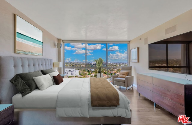 bedroom featuring light wood-type flooring and floor to ceiling windows