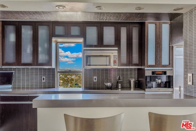 kitchen featuring backsplash, dark brown cabinetry, and appliances with stainless steel finishes