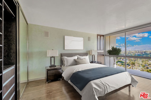 bedroom featuring light hardwood / wood-style flooring and a wall of windows