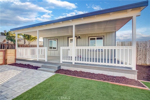 view of front of property with a front lawn, fence, a porch, and board and batten siding