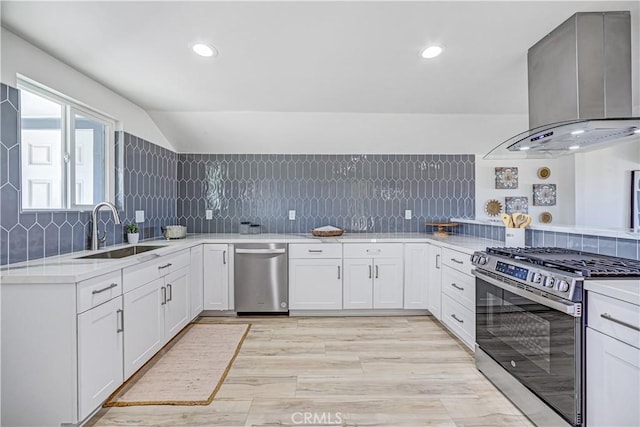 kitchen with tasteful backsplash, wall chimney exhaust hood, stainless steel appliances, light countertops, and a sink