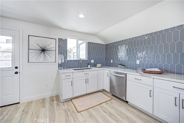 kitchen with a sink, light wood-style floors, light countertops, stainless steel dishwasher, and decorative backsplash