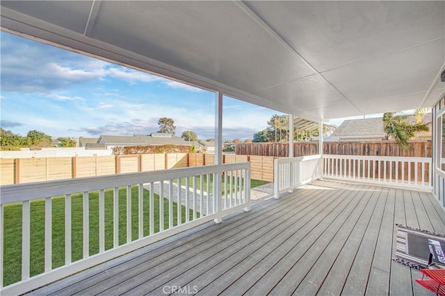 wooden terrace with a lawn and a fenced backyard