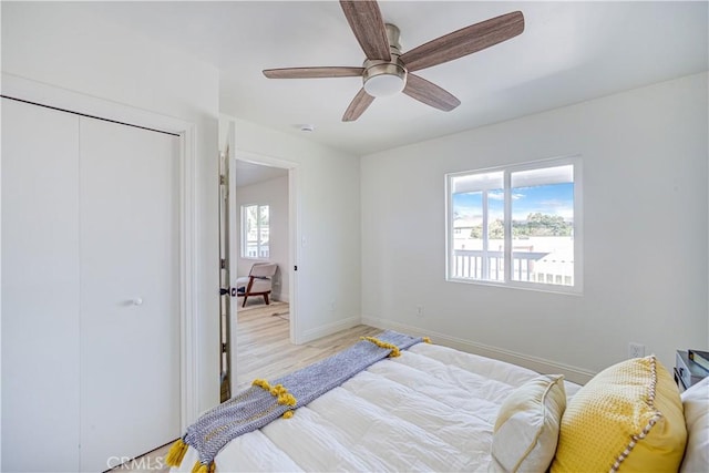 bedroom featuring light wood-style floors, multiple windows, baseboards, and a closet