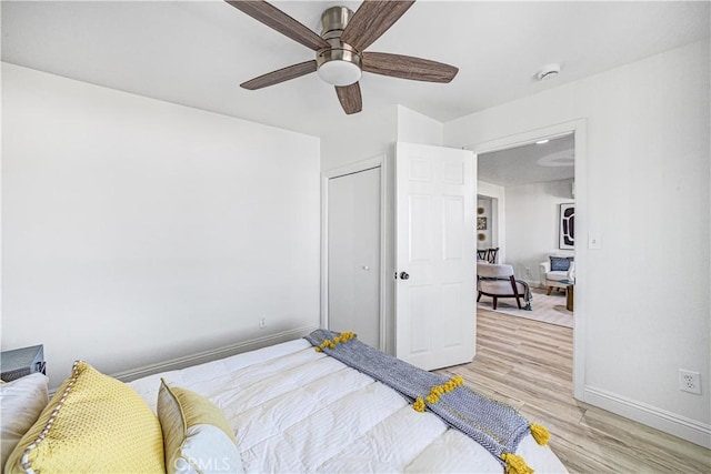 bedroom with light wood-style flooring, baseboards, ceiling fan, and a closet