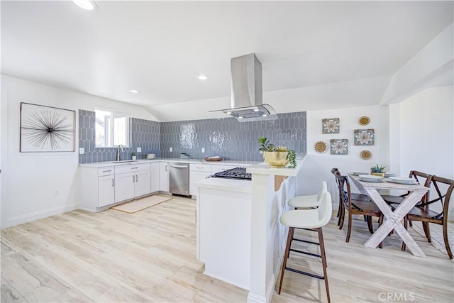 kitchen featuring decorative backsplash, a peninsula, island exhaust hood, light countertops, and a sink